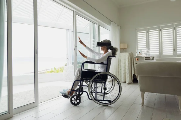 使用室内虚拟现实耳机对坐在轮椅上的妇女的侧视图 正宗的退休老人生活理念 — 图库照片