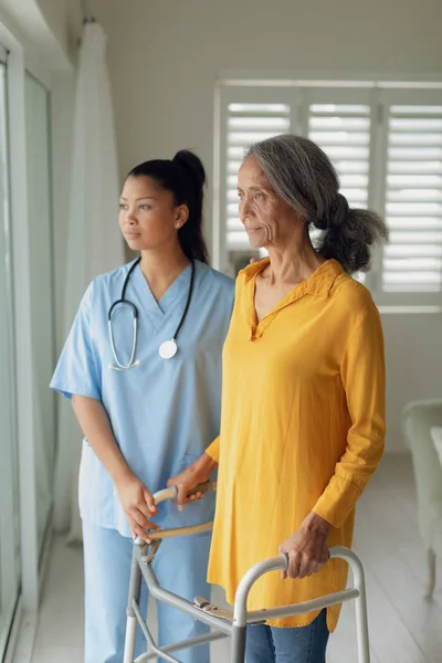 屋内の歩行補助を使用して医療従事者と女性の側面図 本物のシニアリタイアライフコンセプト — ストック写真