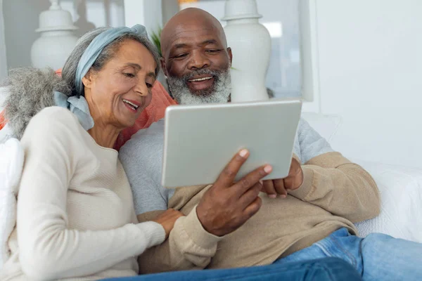 Plaj Evinde Kanepeye Dijital Tablet Kullanarak Çeşitli Kıdemli Çiftin Görünümü — Stok fotoğraf