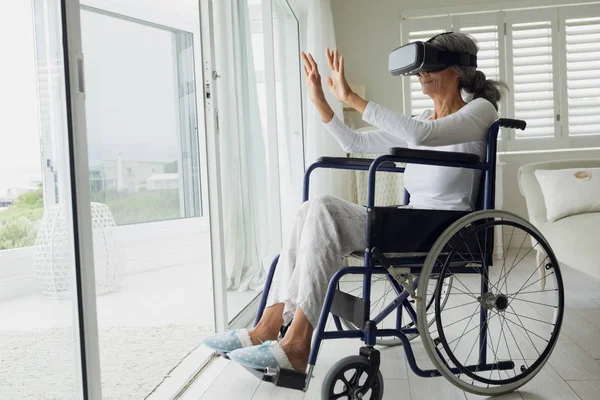 使用虚拟现实面具在室内轮椅上的妇女的侧面视图 正宗的退休老人生活理念 — 图库照片
