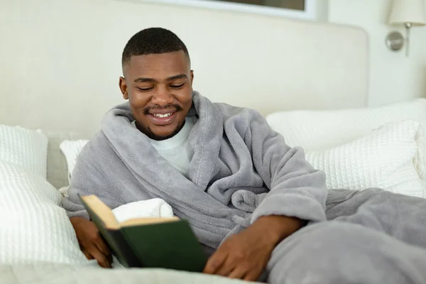 Vista Lateral Del Hombre Afroamericano Feliz Leyendo Libro Mientras Está —  Fotos de Stock