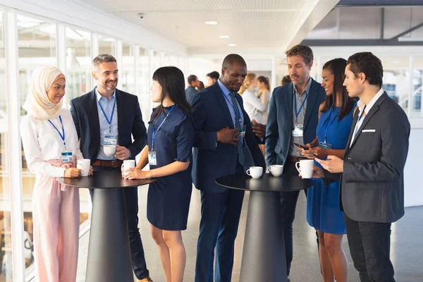 Front view of diverse Business people interacting with each other while having coffee in office.