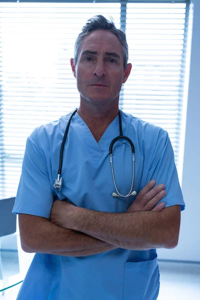 病院で腕を組んだ首の周りに聴診器を持つハンサムな白人男性医師の肖像画 — ストック写真