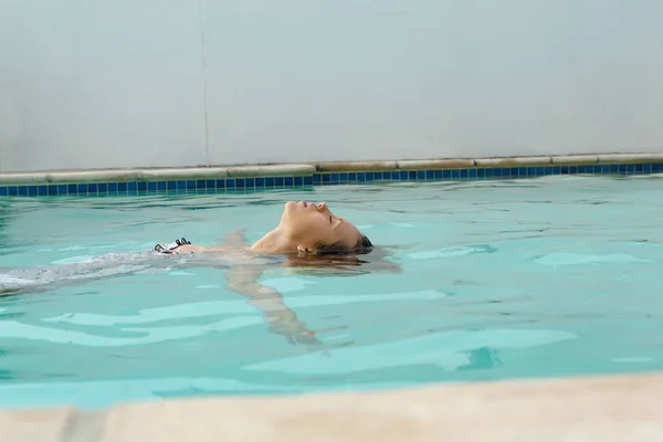 美丽的白种人侧视图与眼睛闭着漂浮在游泳池在后院在家里 — 图库照片