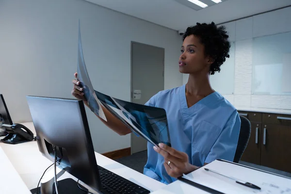 漂亮的非洲裔美国女外科医生在医院办公桌前检查X光片的正面视图 — 图库照片
