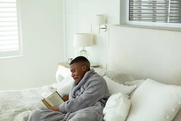 Vista Lateral Del Hombre Afroamericano Leyendo Libro Mientras Está Acostado — Foto de Stock