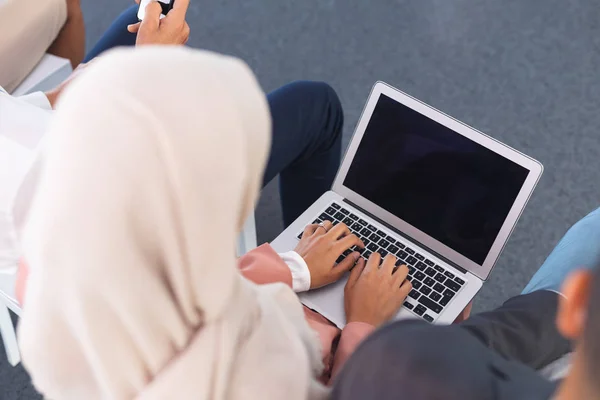 High angle view of mixed-race businesswoman in hijab working on laptop in business seminar.
