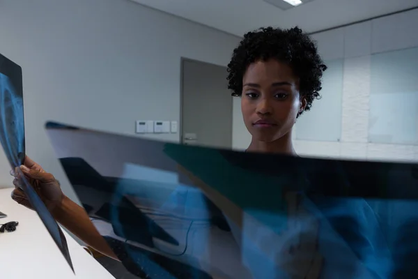 非洲裔美国女外科医生在医院办公桌检查X光片的正面视图 — 图库照片