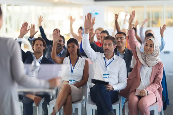 ビジネスカンファレンスで手を挙げる多様な観客の正面図 — ストック写真