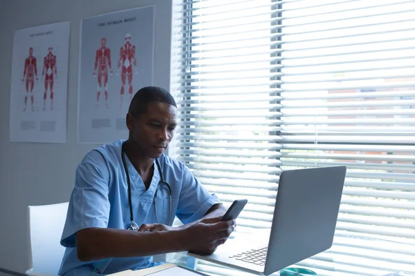 Pohled Afroamerického Mužského Chirurga Který Používá Mobilní Telefon Počítačem Před — Stock fotografie