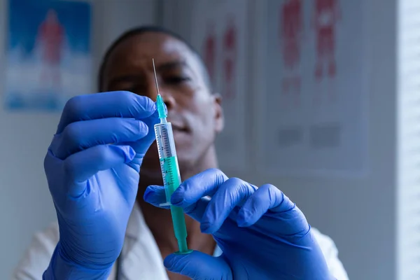 病院で注射器を注射器を持つアフリカ系アメリカ人男性医師のクローズアップ — ストック写真