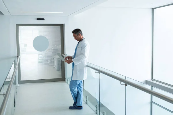 在医院走廊使用笔记本电脑的成熟白人男医生的侧视图 — 图库照片