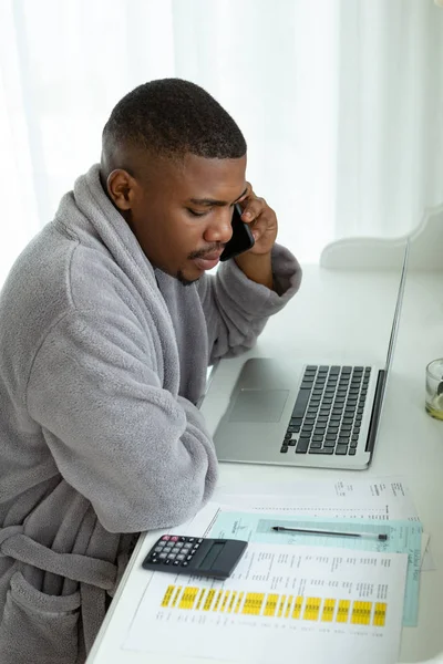 快適な家の寝室の机で携帯電話で話すアフリカ系アメリカ人の男性のサイドビュークローズアップ — ストック写真