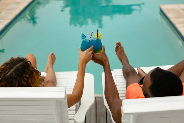 在家庭后院游泳池附近的日光浴躺椅上放松时 各对夫妇敬酒杯的高角度视图 — 图库照片