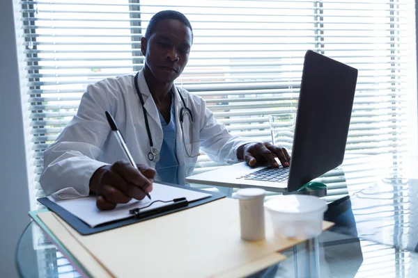 Vista Frontal Del Médico Afroamericano Escribiendo Portapapeles Con Bolígrafo Mientras —  Fotos de Stock