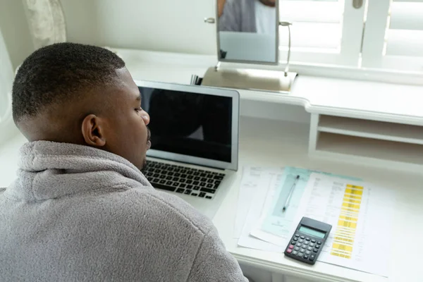 快適な家の寝室の机の上の紙幣を見てアフリカ系アメリカ人の男性の背面図 — ストック写真