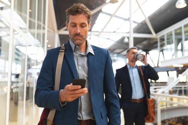 Vista Frontal Empresário Caucasiano Usando Telefone Celular Enquanto Caminha Corredor — Fotografia de Stock