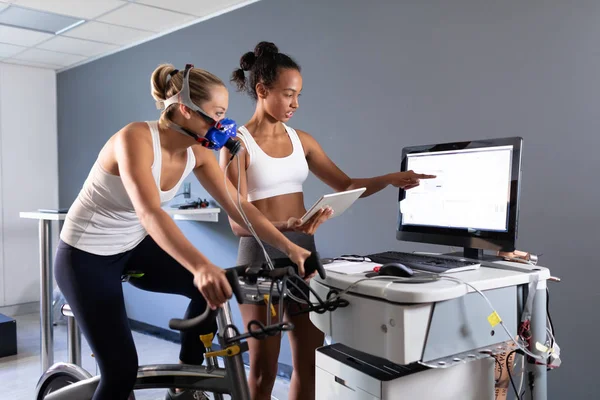자전거를 모니터에 연결된 마스크를 사용하여 피트니스 테스트를하는 여성의 측면보기와 스포츠 — 스톡 사진