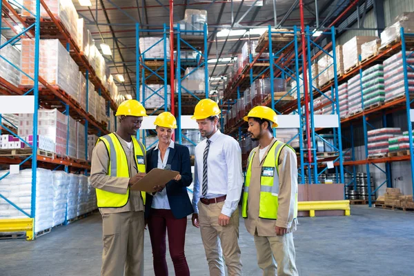 Front view of diverse staffs working together on clipboard in warehouse.