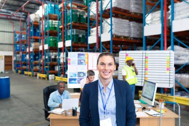 Portrait of happy mature Caucasian female manager looking at camera in warehouse. clipart