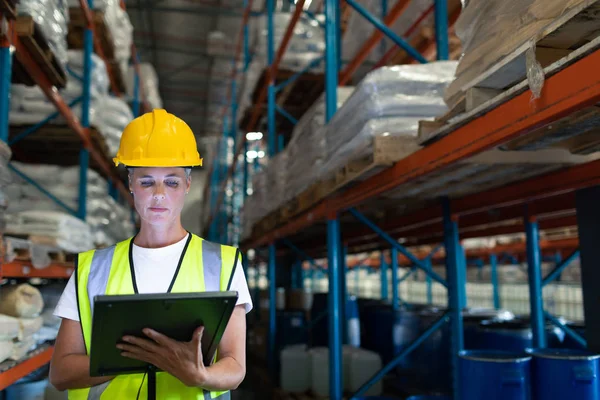 Front view of Caucasian Attentive female staff using digital tablet in warehouse.