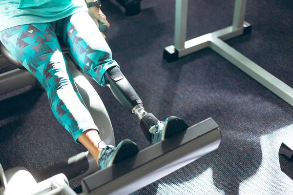 フィットネススタジオで脚プレス機で運動する脚切断患者を持つ障害のあるアクティブな女性の低いセクション — ストック写真
