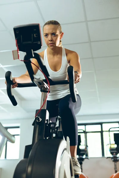 低角度视图美丽的年轻高加索妇女锻炼与健身工作室锻炼自行车 — 图库照片