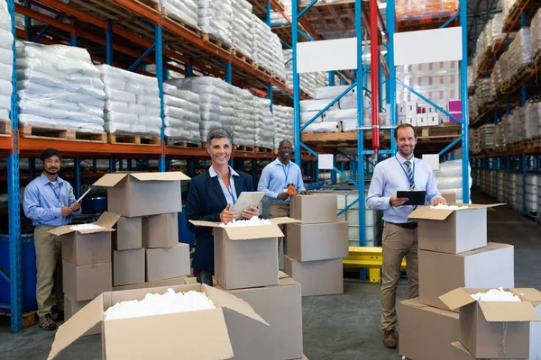 Front view of mature diverse staff looking at camera while working together in warehouse.