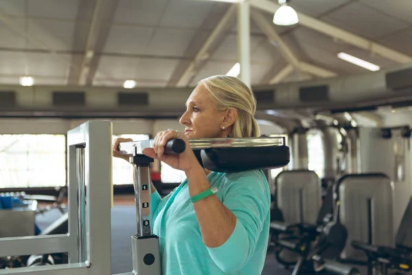 活跃高级白种妇女与腿截肢者行使在健身工作室蹲机的侧视图 — 图库照片