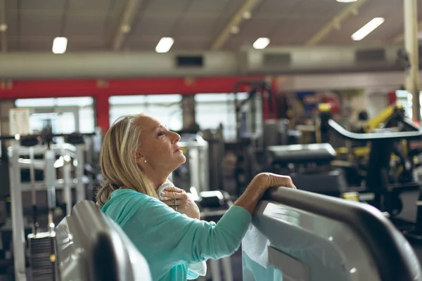 侧视图疲惫活跃的高级白种妇女擦汗巾在健身室 — 图库照片