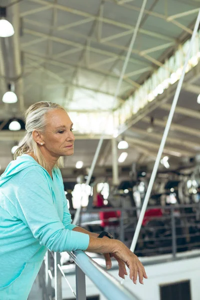 在健身工作室里 有思想的活跃高级白种妇女靠在栏杆上的侧视图 — 图库照片