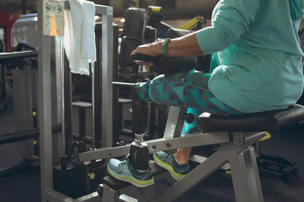 残疾活跃妇女与截肢腿在健身工作室用腿卷曲机锻炼的低部分 — 图库照片