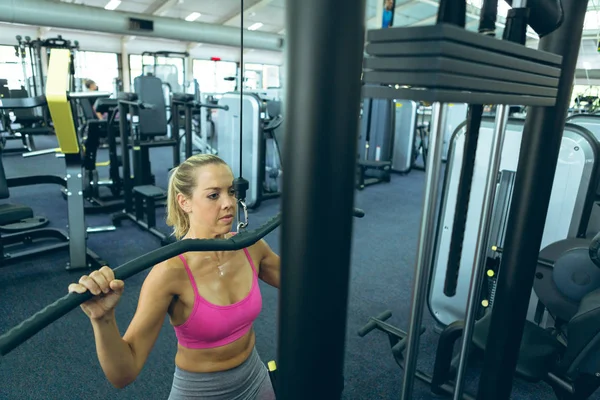 美丽的年轻高加索女运动员在健身工作室使用拉下机锻炼的前视图 — 图库照片
