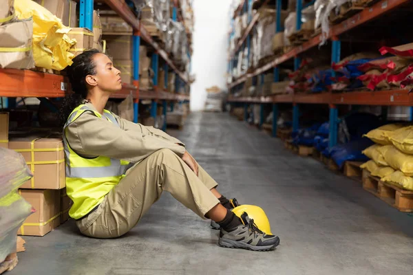 倉庫で目を閉じて座っている疲れた女性スタッフ — ストック写真