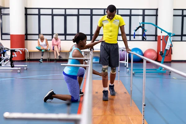 Boční Pohled Afroamerického Ženského Fyzioterapeuta Pomáhajícího Hendikepovanému Afroameričanovi Chodit Paralelními — Stock fotografie