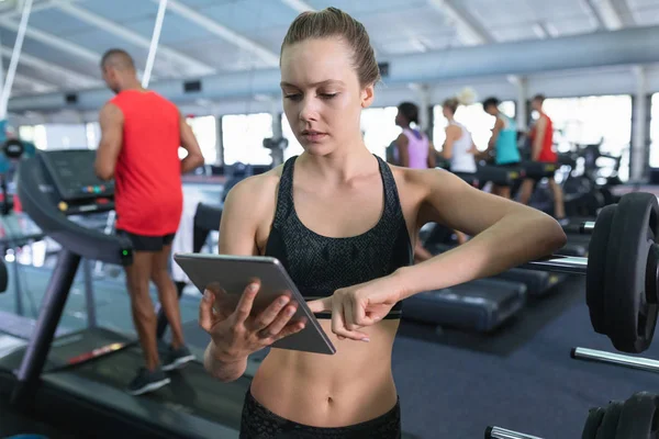 在健身中心使用数码平板电脑观看美丽的高加索女教练 健康的人锻炼身体和训练的明亮的现代体育馆 — 图库照片