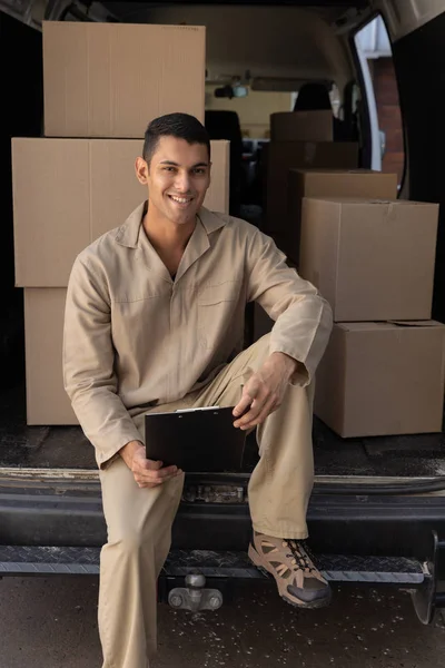 Happy Delivery Man Med Urklipp Tittar Kameran Utanför Lagret — Stockfoto