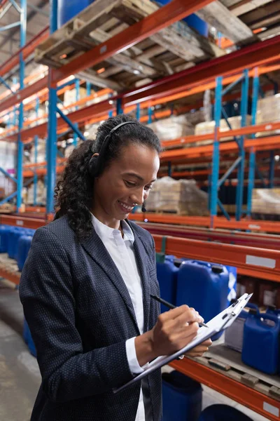 Directora Afroamericana Escribiendo Portapapeles Mientras Habla Con Auriculares Almacén — Foto de Stock