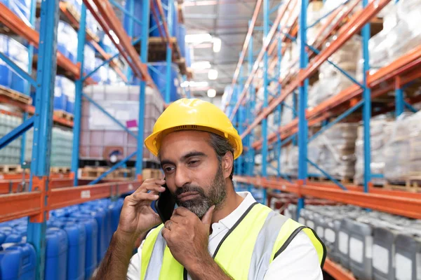 倉庫で携帯電話で話す思慮深い男性労働者 — ストック写真