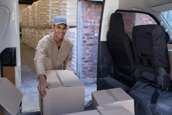 送货员从仓库外的货车上卸下纸板箱的正面视图 — 图库照片