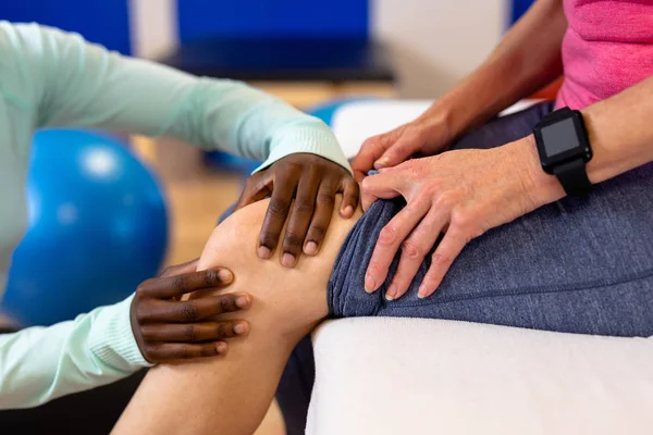 スポーツセンターで活躍中の女性に脚マッサージを施す女性理学療法士のクローズアップ — ストック写真