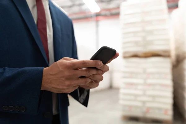 倉庫で携帯電話を使用するビジネスマンのミッドセクション — ストック写真