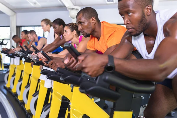 在健身中心 不同体形的人骑自行车锻炼的侧视图 明亮的现代健身房 健身健美的人锻炼身体 在旋转课上训练 — 图库照片