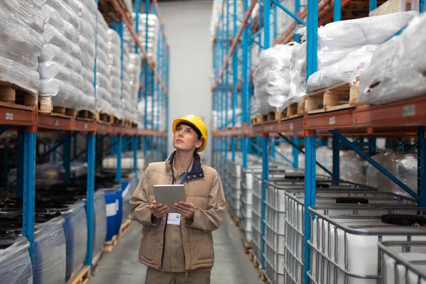 倉庫で見上げるデジタルタブレットを持つ女性労働者の正面図 — ストック写真