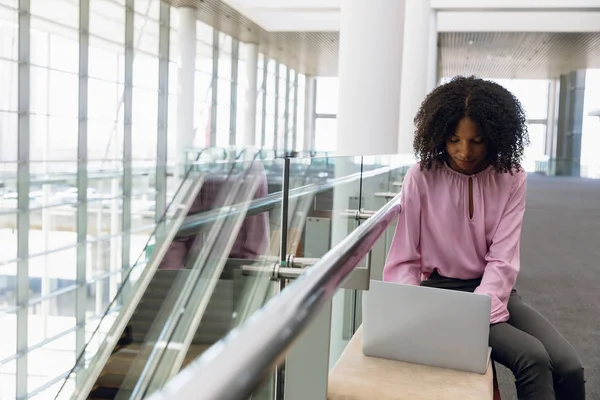 坐在现代办公室大厅里的年轻非洲裔女商人坐在笔记本电脑前 — 图库照片