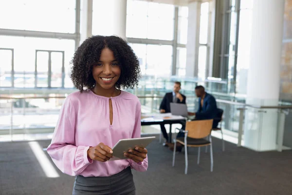 一位年轻的非洲裔美国女商人站在现代化的办公室里 手里拿着平板电脑 微笑着对着镜头 — 图库照片