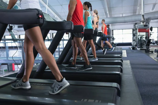 在健身中心的跑步机上一起锻炼的人们的侧观 — 图库照片