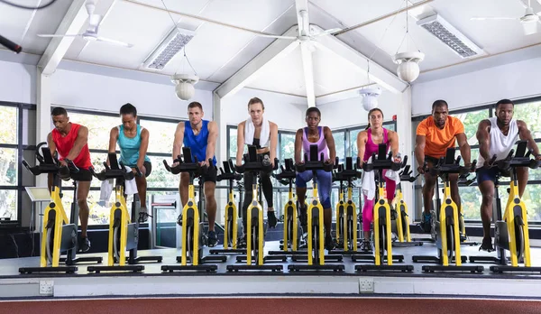 在健身中心 不同体形的人在运动自行车上锻炼的前景十分广阔 明亮的现代健身房 健身健美的人锻炼身体 在旋转课上训练 — 图库照片