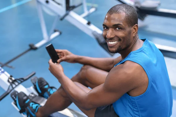 Spor Salonunda Kürek Çekerken Cep Telefonu Kullanan Afro Amerikan Fit — Stok fotoğraf