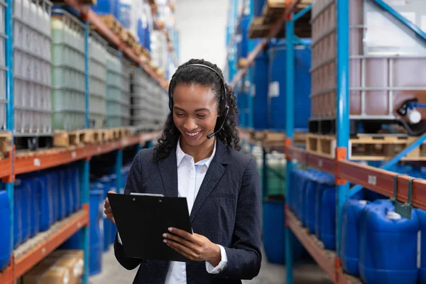 Gelukkige Vrouwelijke Manager Schrijven Het Klembord Tijdens Het Praten Headset — Stockfoto